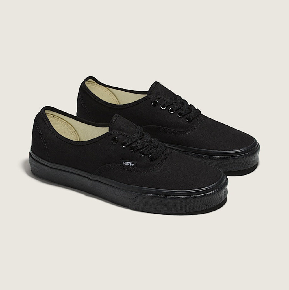 Pair of black sneakers on a light beige background
