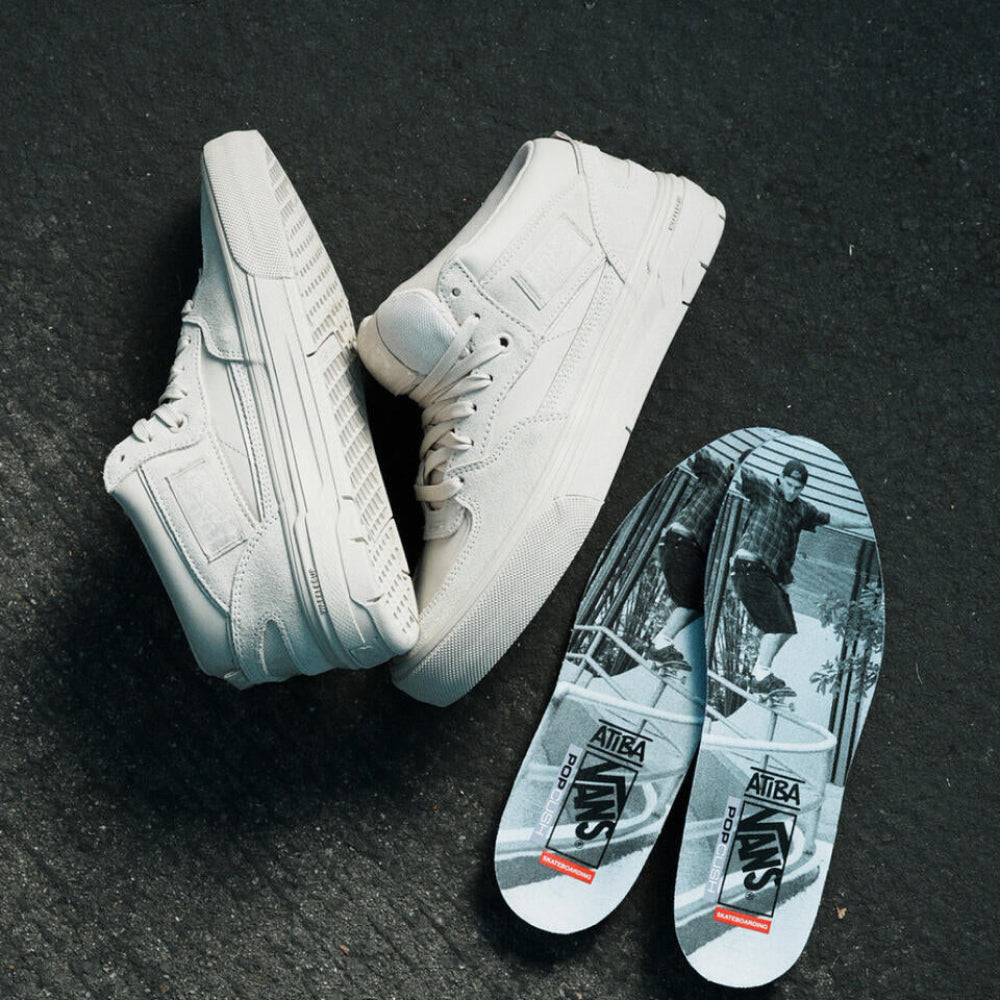 White high-top sneakers with branded insoles on a dark surface